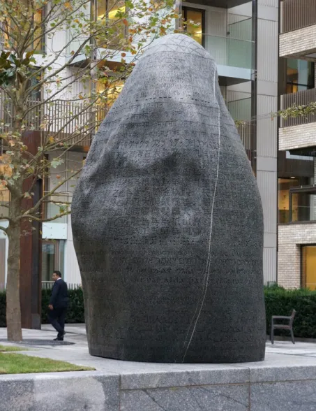 large dark boulder with engraved inscriptions in various languages
