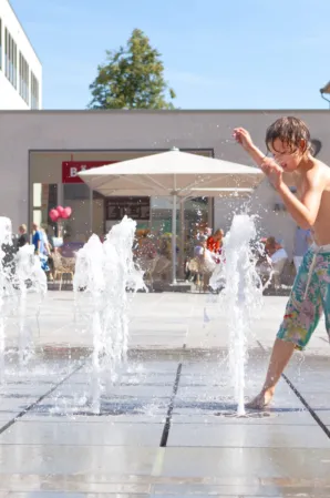 water feature with interactive fountains on which a child is playing