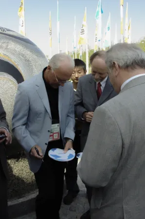 Franz Beckenbauer signing an autograph with a floating sphere in the background
