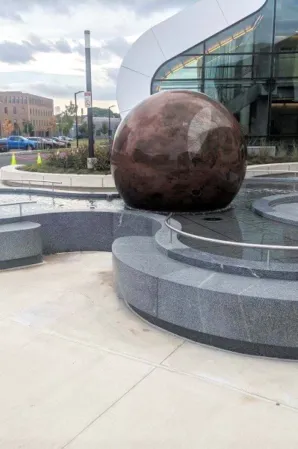 Red floating granite sphere in an organically shaped water basin