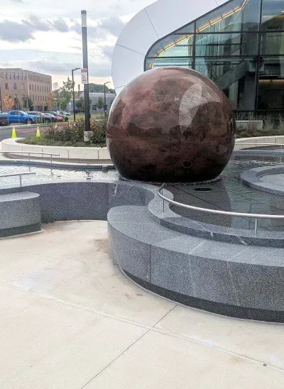 Red floating granite sphere in an organically shaped water basin
