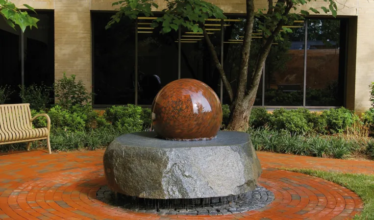 Rotating red granite sphere in a fountain installation