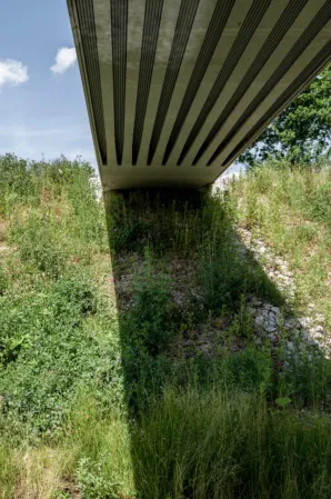 Underside view of a post-tensioned granite bridge with visible prestressing strands