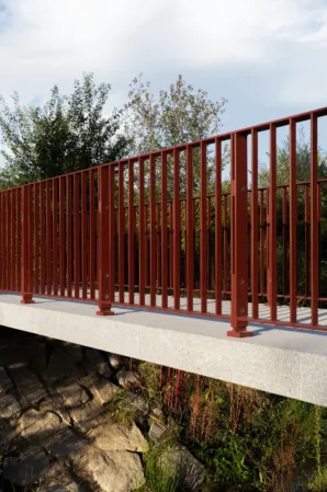 Side view of a granite bridge with red railings
