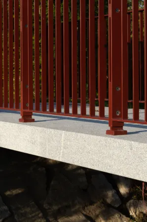 Side view of a granite bridge with red railings