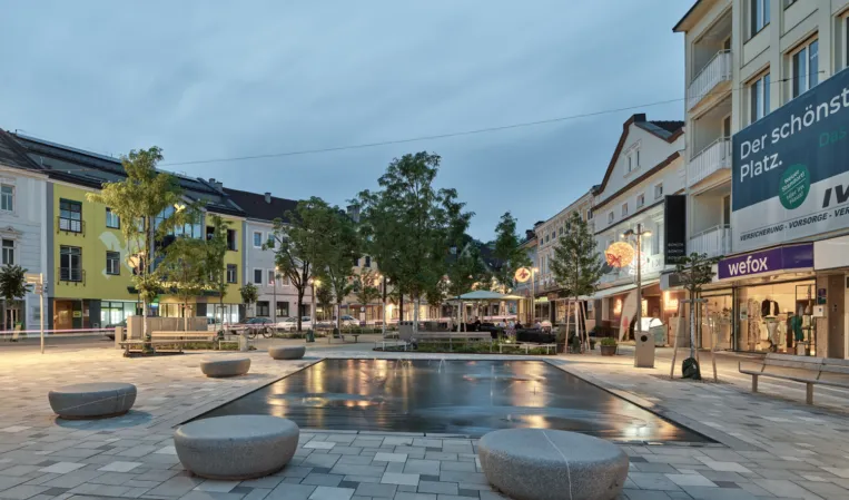 Granite water jet field with stone seating bollards at night