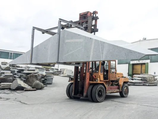 heavy-duty forklift lifting a large granite element