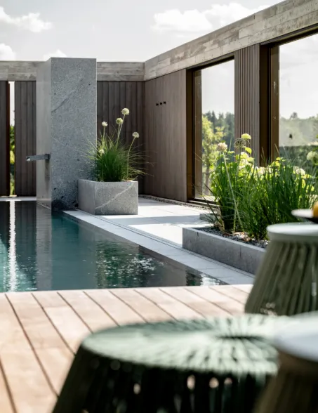 Outdoor pool area with a granite shower and planters