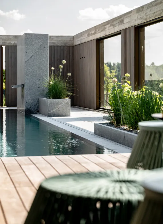 Outdoor pool area with a granite shower and planters