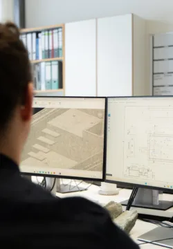 Engineer working on technical drawings and CAD designs at a dual-monitor workstation
