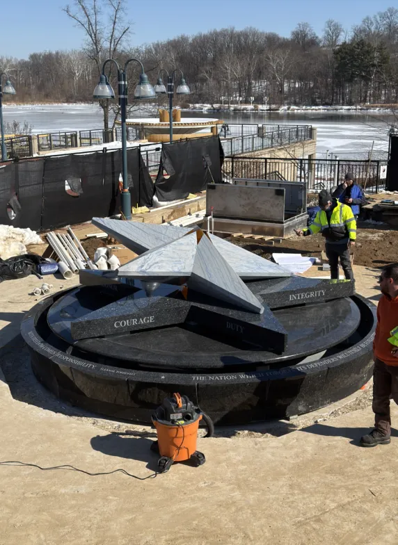 Installation of a large granite fountain with geometric sculptural elements at a construction site