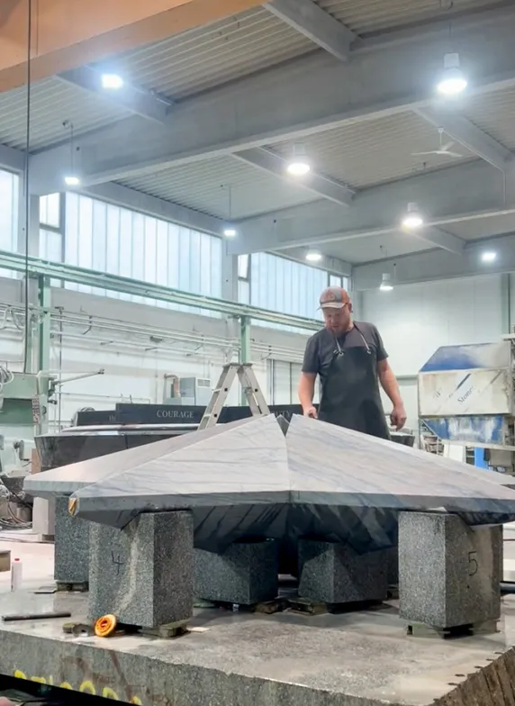 Worker inspecting a large granite star in a stone processing workshop