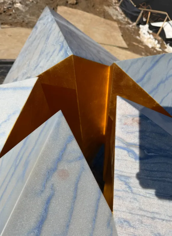 Angular sculpture on a veined blue marble surface.