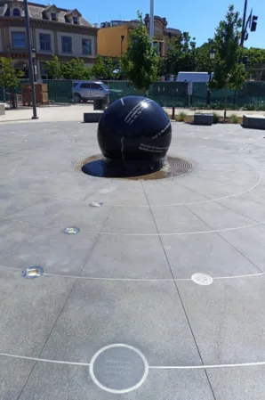 Polished black granite sphere fountain in a paved public square
