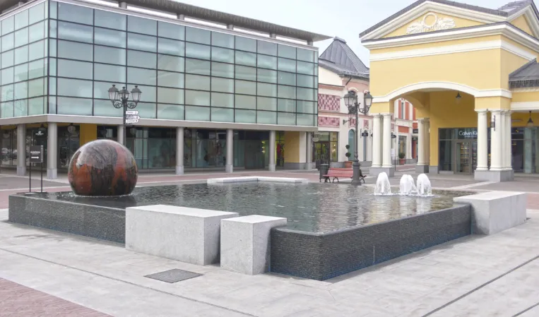 Granite sphere fountain with water jets in a rectangular reflecting pool at an outdoor shopping plaza