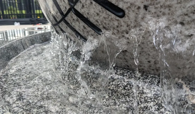 Close-up of water flowing over a granite baseball sphere fountain
