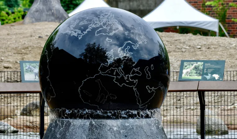 Close-up of a polished black granite sphere fountain with an engraved world map