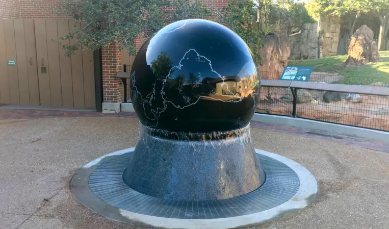Polished black granite sphere fountain with an engraved world map