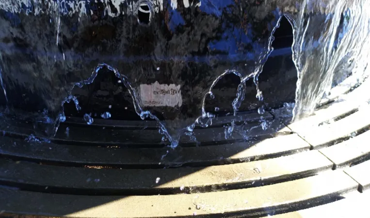 Close-up of water flowing over a polished black granite sphere fountain