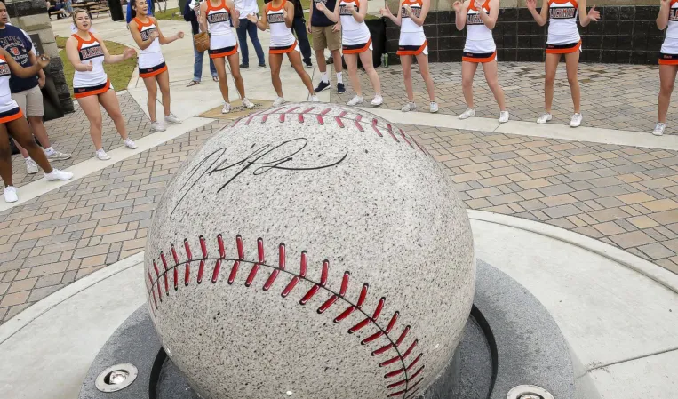 Granite sphere fountain shaped like a baseball with cheerleaders standing in the background