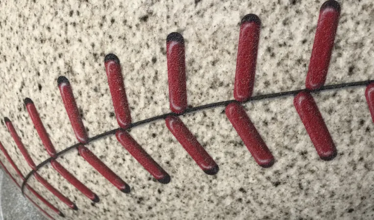 Close-up of red baseball stitching engraved into a granite sphere fountain