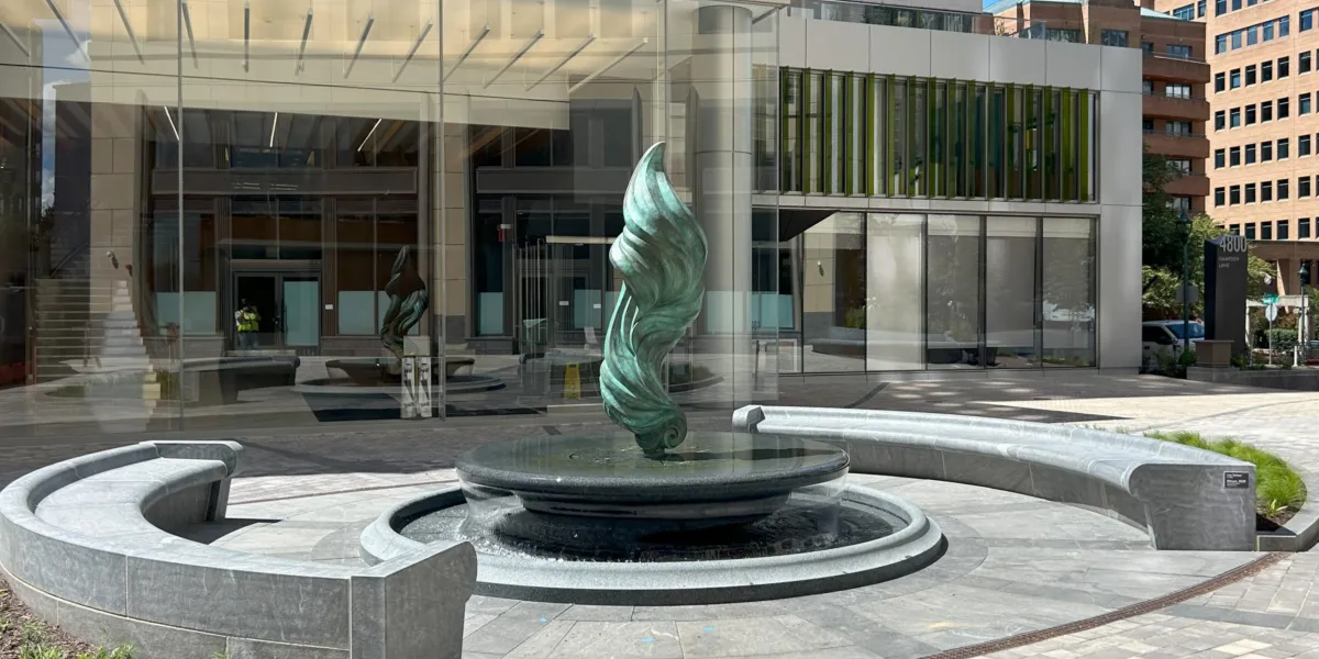 Sculptural fountain with a bronze centerpiece and circular granite basin in an urban plaza