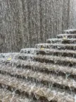 Water cascading down multiple stepped stone ledges, creating a textured waterfall with flowing streams and white foam.