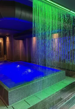 Indoor granite pool with illuminated waterfall in blue and green lighting
