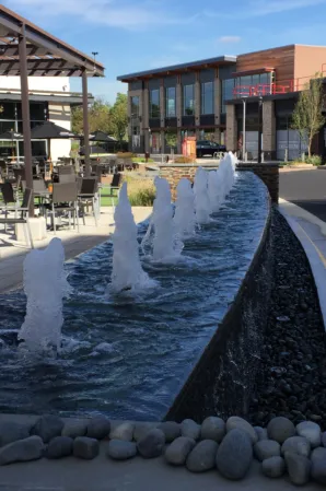 Long rectangular fountain with rows of water jets in a modern outdoor plaza