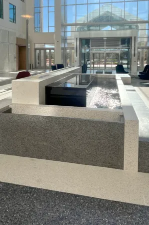 Rectangular granite fountain with flowing water in a spacious modern atrium with glass walls