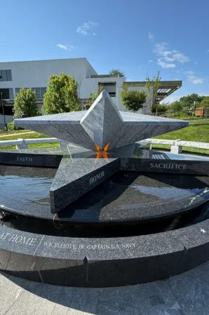 Angular granite sculpture with bronze details in a circular fountain basin