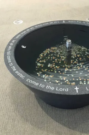 Circular black granite fountain with engraved biblical text and a central water feature