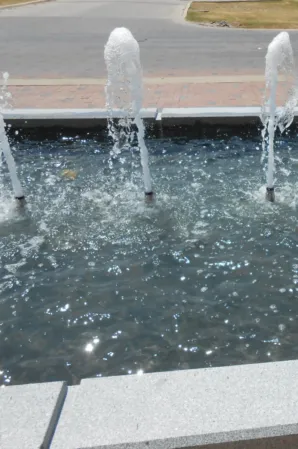 Close-up of water jets bubbling into a granite fountain basin