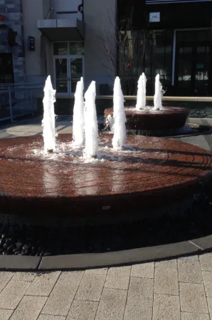 Two circular granite fountains with vertical water jets in an outdoor plaza