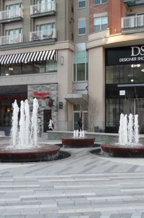 Circular fountains with water jets and outdoor seating in a modern shopping plaza