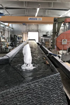 Granite fountain with a water jet undergoing testing in a stone fabrication workshop
