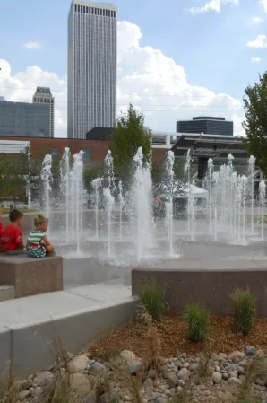 Urban splash fountain with multiple water jets and a city skyline in the background