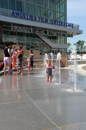 Children playing among interactive water jets in front of the Angelus Temple building
