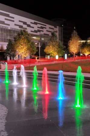 Colorful illuminated water jets in an interactive fountain plaza at night