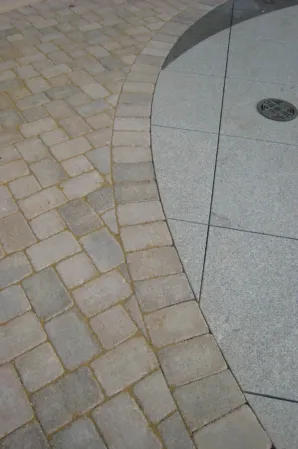 Close-up of curved granite paving with an integrated fountain nozzle surrounded by stone pavers