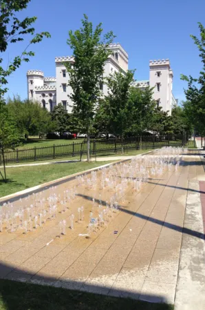 Rectangular interactive fountain with multiple water jets in a landscaped plaza near a historic building
