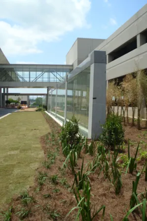 Glass water wall beside a landscaped courtyard and modern office buildings