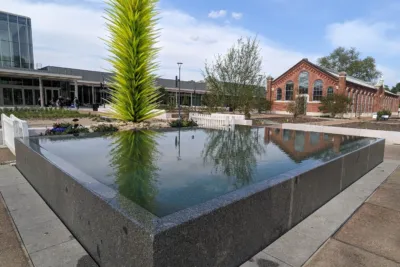 Raised granite reflecting pool with a green sculpture in a modern urban plaza