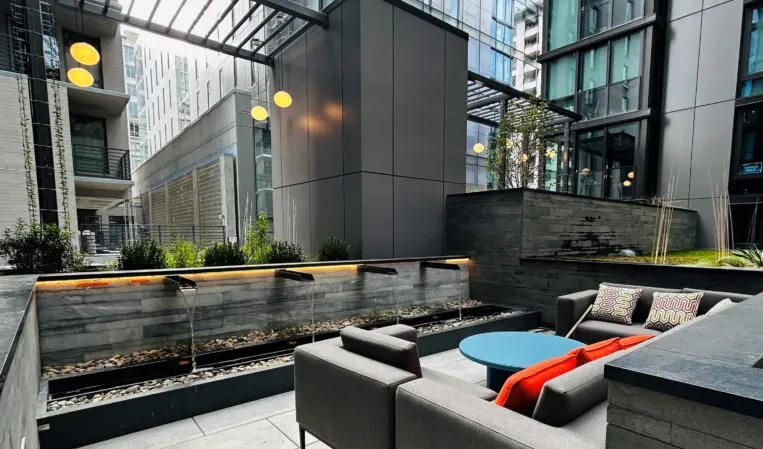 Modern outdoor lounge with granite water walls, fire features and seating in an urban courtyard
