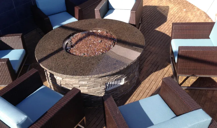 Circular stone fire pit surrounded by wicker lounge chairs on an outdoor terrace