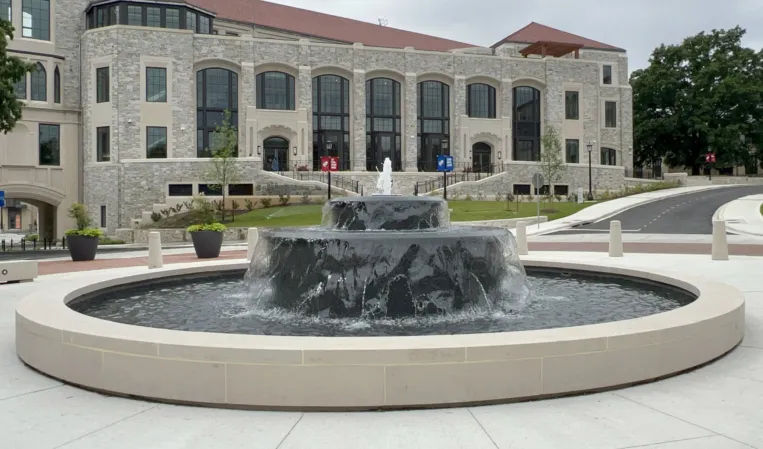 Circular stone fountain with cascading water in front of a historic building