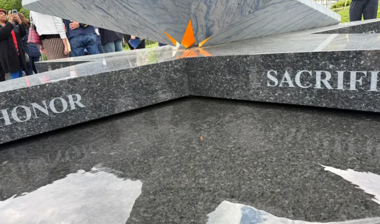 Close-up of a polished granite memorial fountain with engraved inscriptions and a sculptural stone element