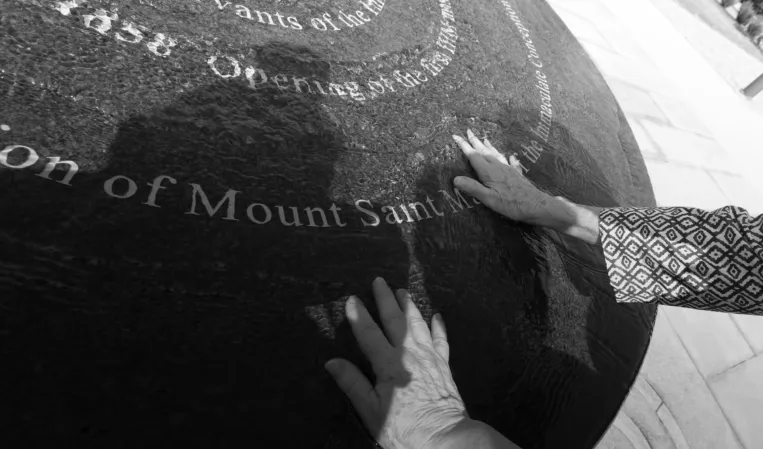 Hands touching engraved text on a polished black granite sphere