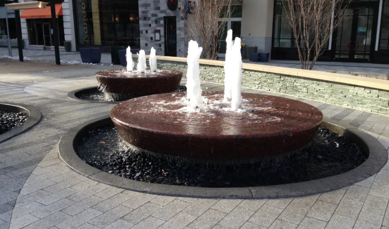 Two circular granite fountains with vertical water jets in an outdoor plaza