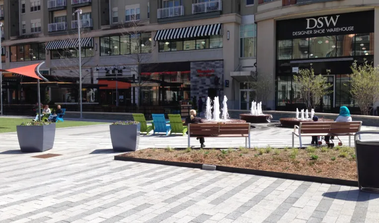 Circular fountains with water jets and outdoor seating in a modern shopping plaza
